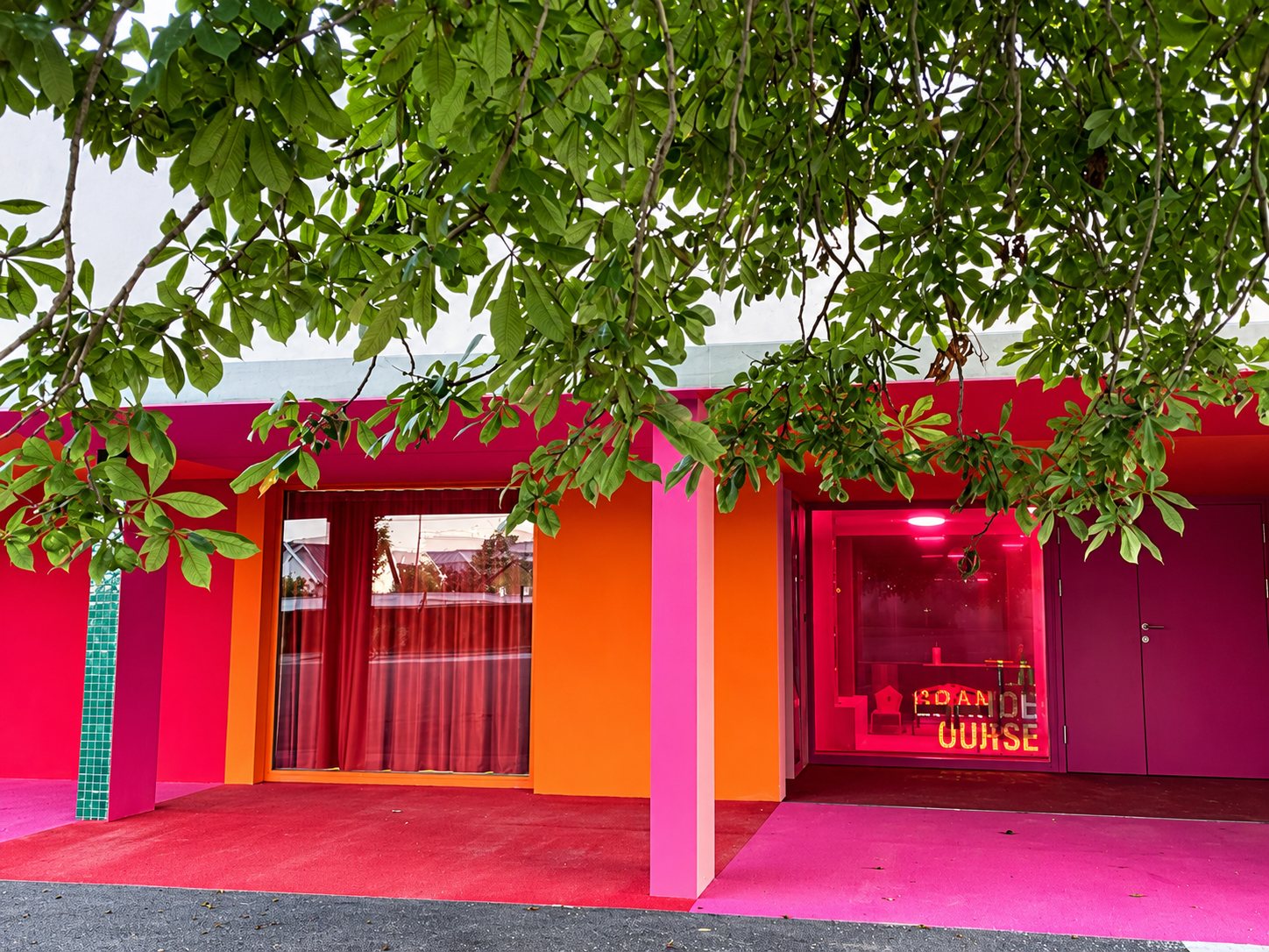 L’entrée de La Grande Ourse : façade rose, orange et rouge avec l’enseigne « La Grande Ourse » derrière la vitre